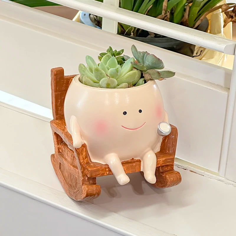 Ceramic planter with a smiling face and succulents on a wooden rocking chair.