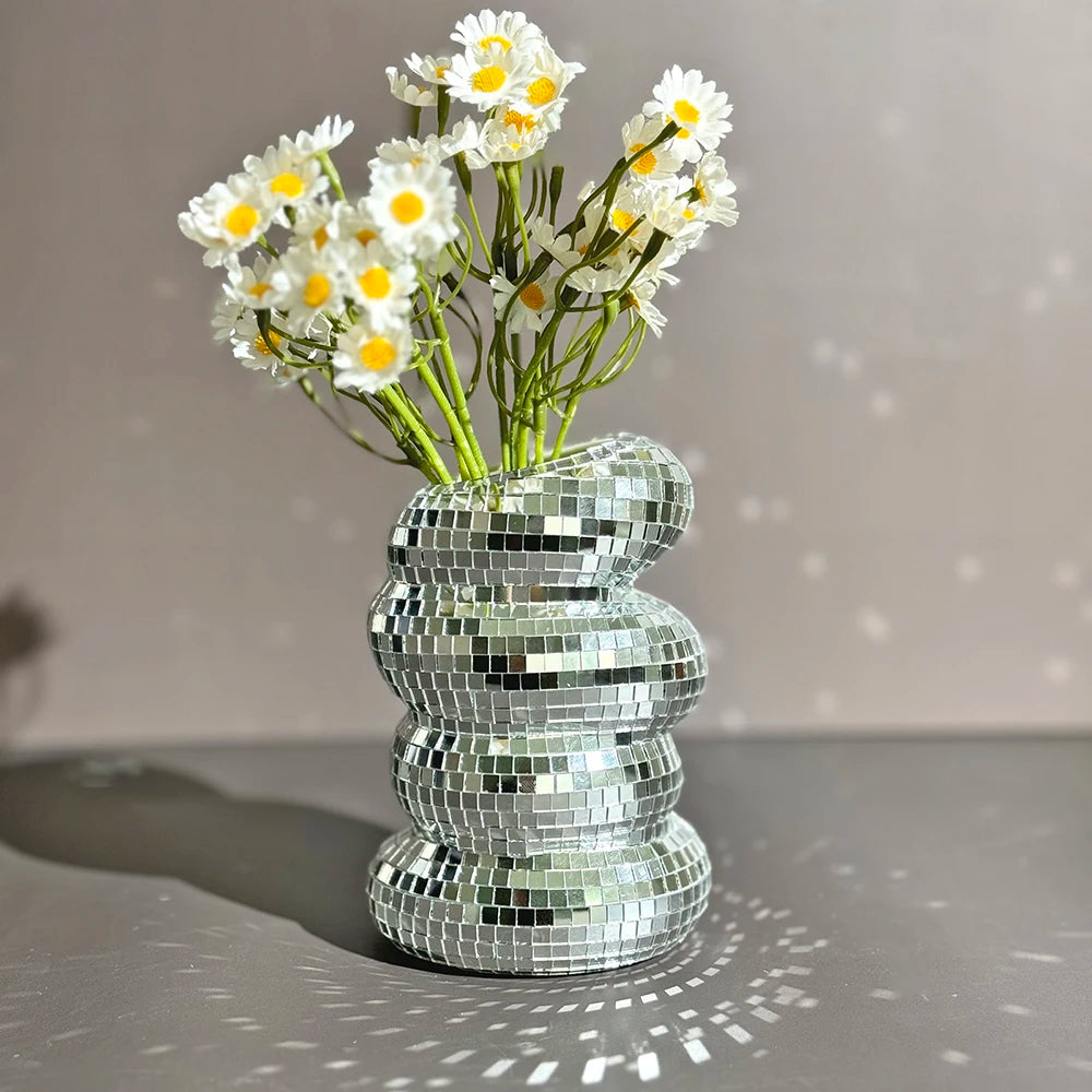 Silver disco ball vase with flowers on a gray surface